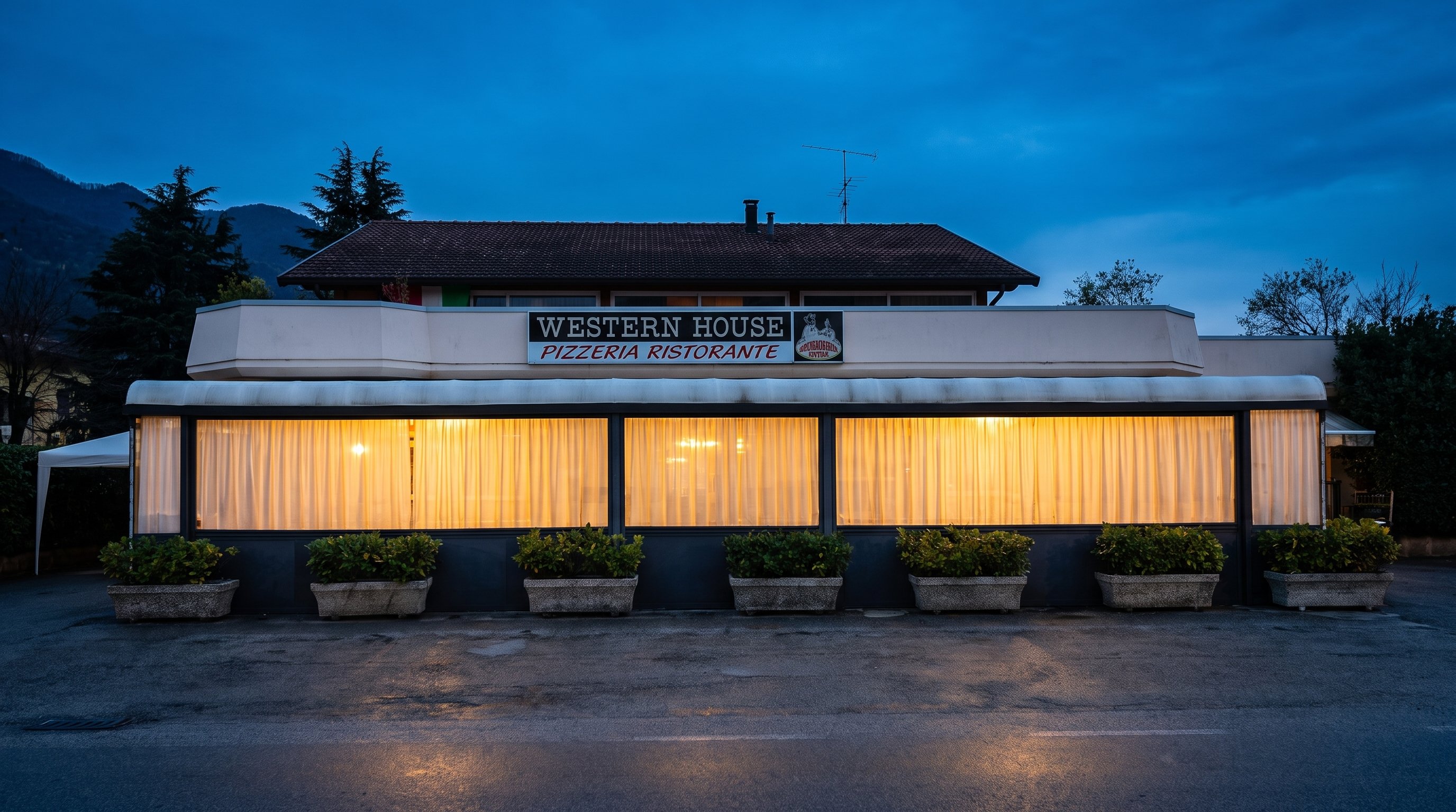 Western House exterior at blue hour — the glowing veranda under the mountains